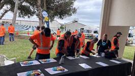 A group of people in orange vests standing around a table with papers

AI-generated content may be incorrect.
